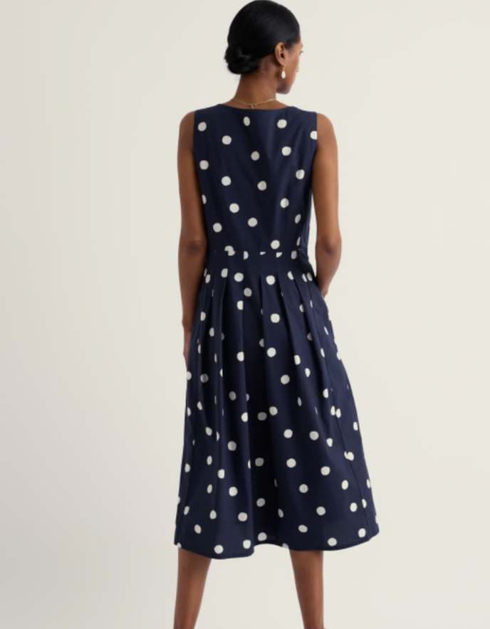 Navy polka dot dress worn by a model on a white background