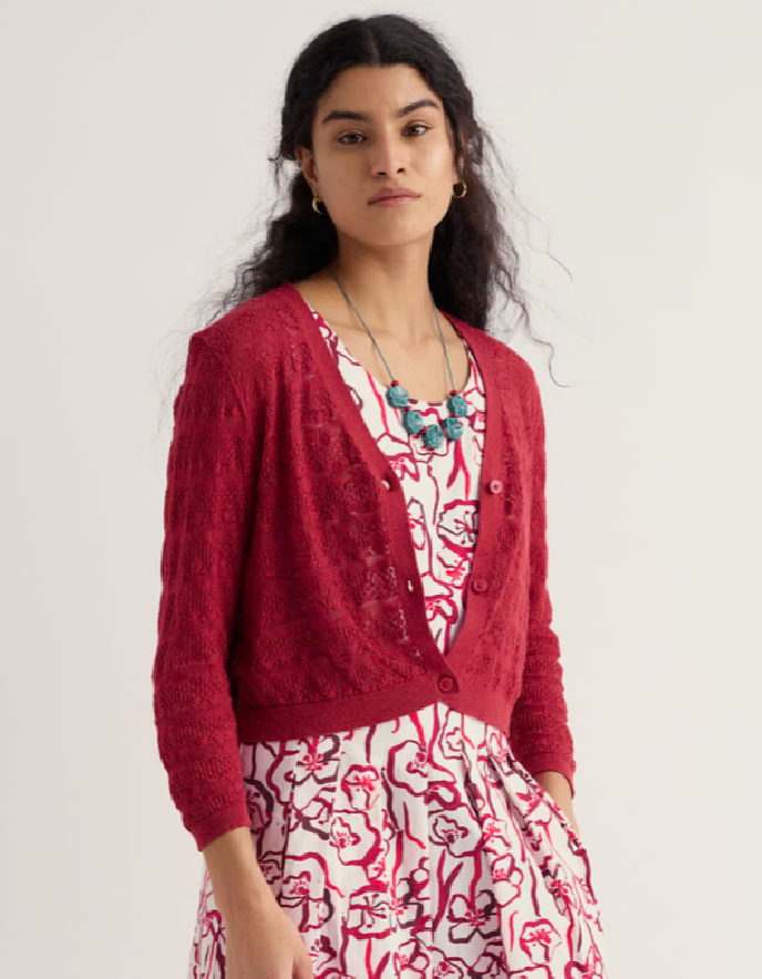 Woman wearing a red cardigan over a floral dress on a white background