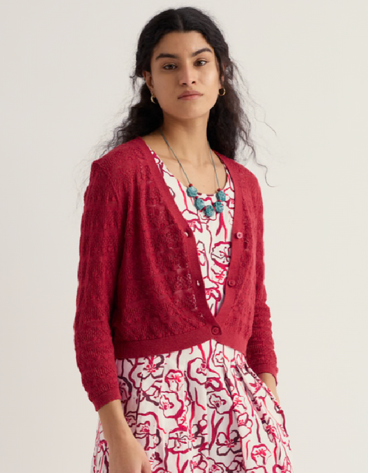 Woman wearing a red cardigan over a floral dress on a white background