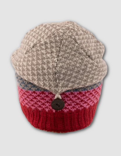 Knitted hat with beige top and red bottom on a light gray background