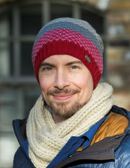 Man wearing a colorful knit beanie and scarf with a blurred background