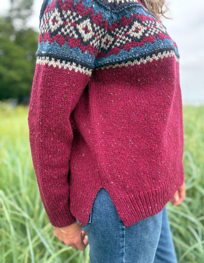 Person wearing a red Fair Isle patterned sweater standing in a grassy field