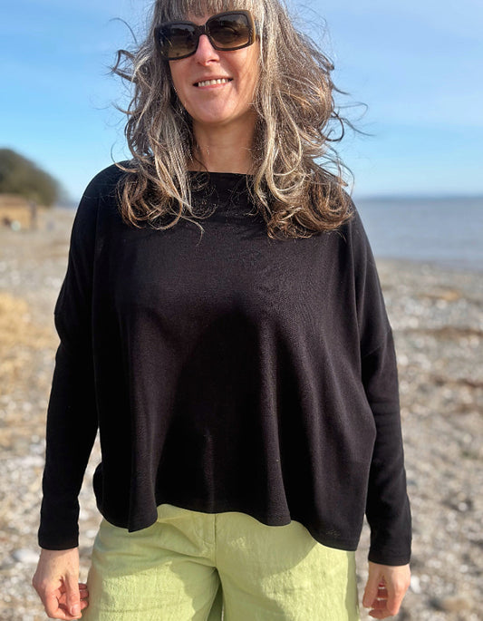 boxy black knit sweater with soft green trousers 