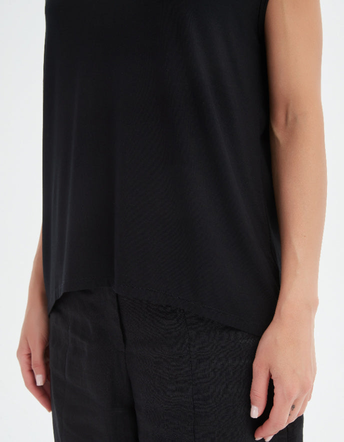 Person wearing a black sleeveless top and black pants on a white background