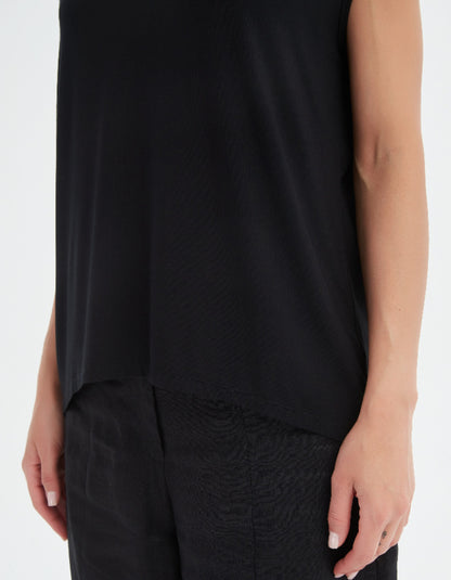 Person wearing a black sleeveless top and black pants on a white background