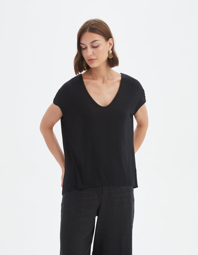 Woman wearing a black V-neck top and black pants on a white background