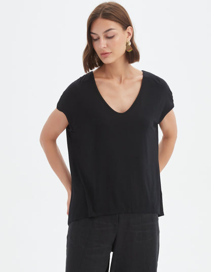 Woman wearing a black V-neck top against a white background