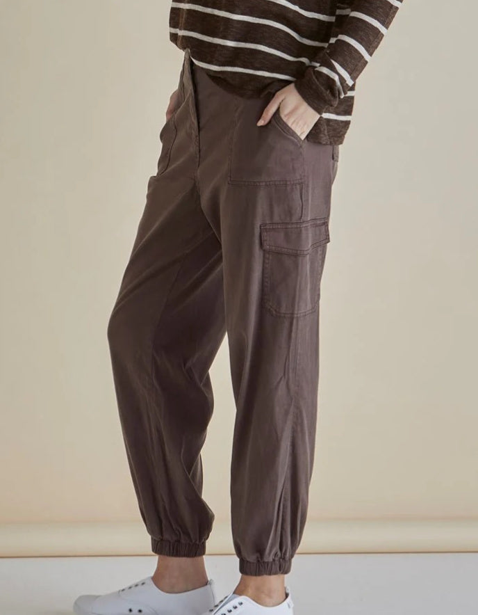 Woman wearing a striped sweater and brown cargo pants against a beige background