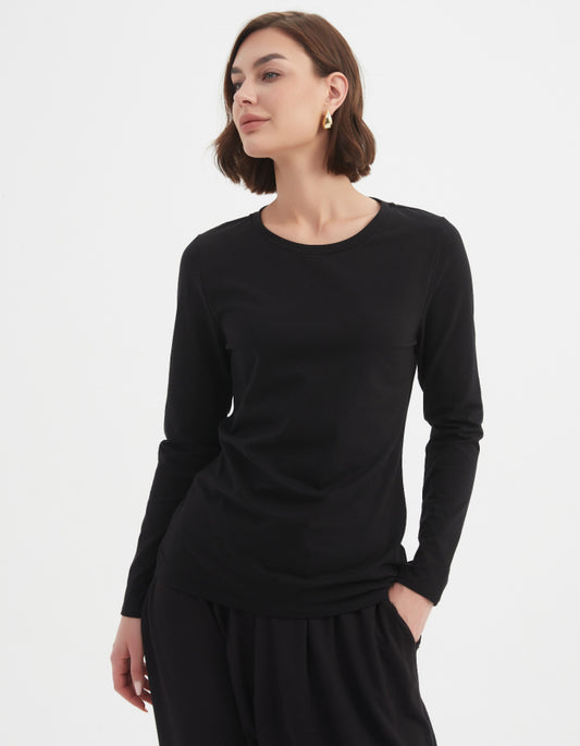Woman wearing a black long-sleeve top and black pants on a white background