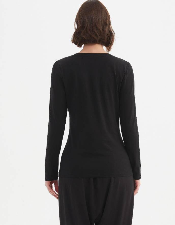 Person wearing a black long-sleeve top and black pants on a white background