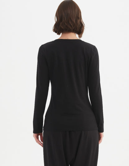 Person wearing a black long-sleeve top and black pants on a white background