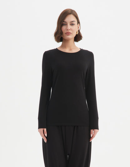 Woman wearing a black long-sleeve top and black pants on a white background