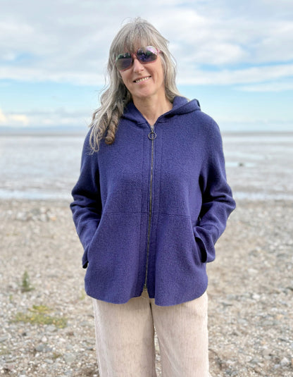 Person wearing a blue hooded boiled wool jacket on a beach