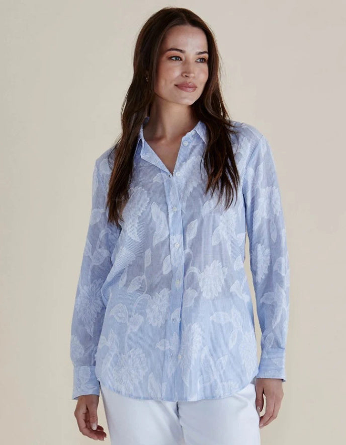 Woman wearing a light blue floral blouse against a beige background