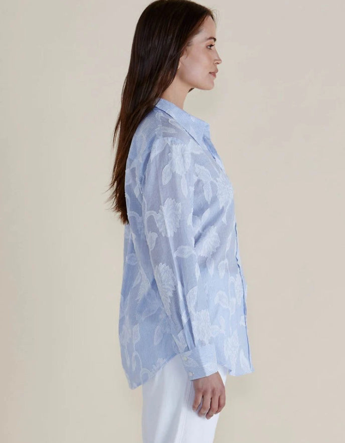 Woman wearing a light blue floral blouse against a beige background