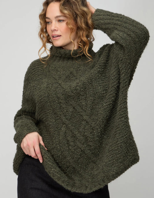 Woman wearing a green knitted sweater against a plain background