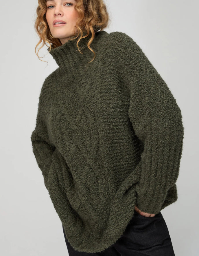 Person wearing a green knitted sweater on a plain background