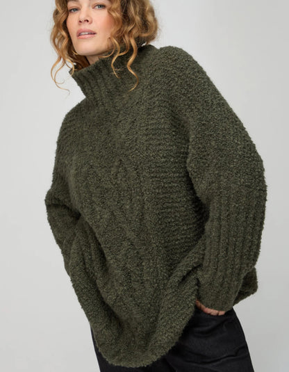 Person wearing a green knitted sweater on a plain background