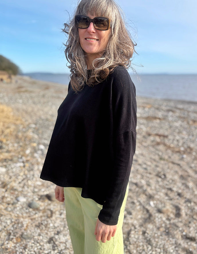 boxy black knit sweater with soft green trousers 