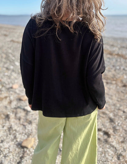 boxy black knit sweater with soft green trousers 