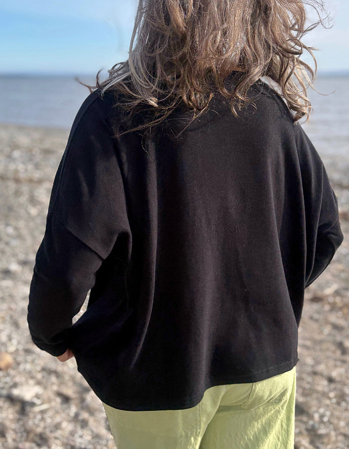 boxy black knit sweater with soft green trousers 