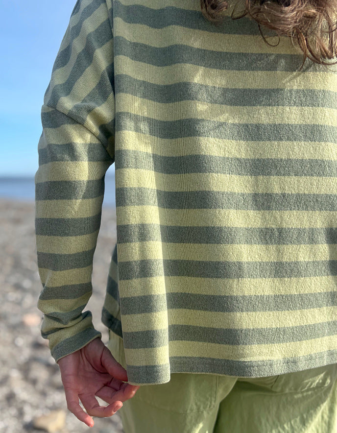 woman wearing stripe green and yellow boxy knit jumper with soft green wide leg trousers