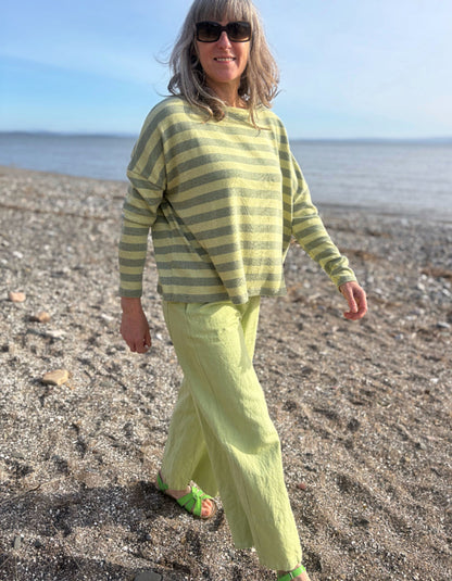 woman wearing stripe green and yellow boxy knit jumper with soft green wide leg trousers