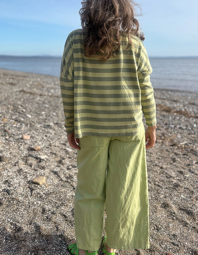 woman wearing stripe green and yellow boxy knit jumper with soft green wide leg trousers
