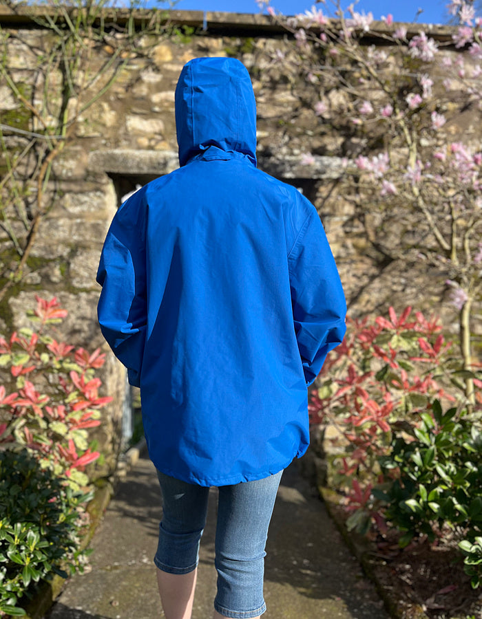 smock style waterproof jacket in coral blue, suitable for men and women, half zip, front punch pocket and kangaroo pocket, taped seams