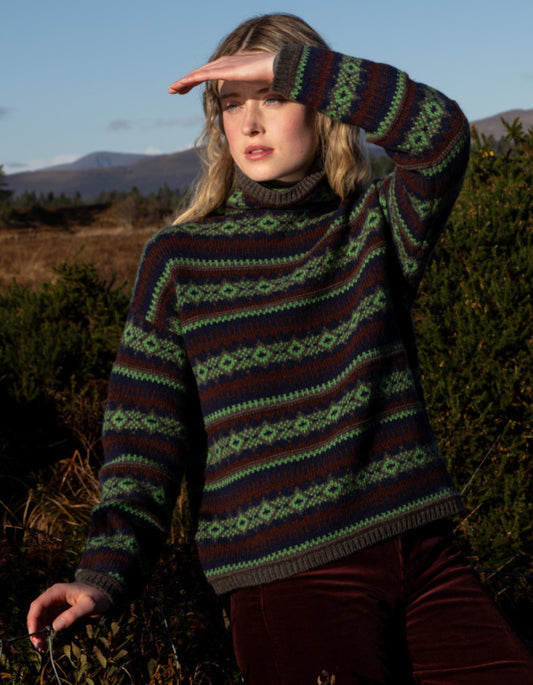 Woman wearing a patterned fair Isle sweater in a natural setting with mountains in the background