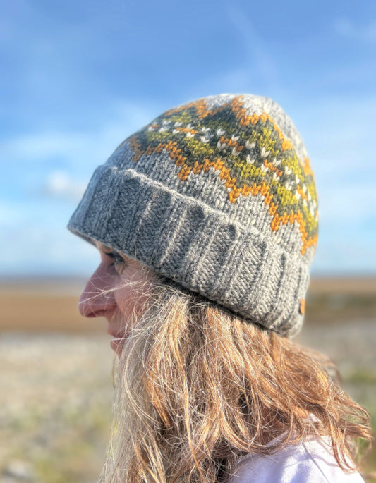 Person wearing a patterned knit beanie against a blue sky