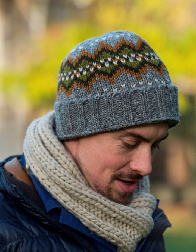 Man wearing a patterned knit hat and scarf outdoors