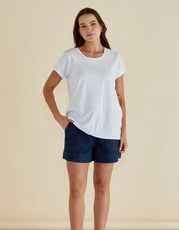 Woman wearing a white t-shirt and blue shorts on a beige background