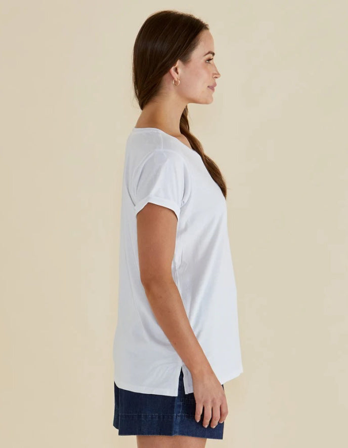 Woman wearing a white blouse and dark shorts against a beige background