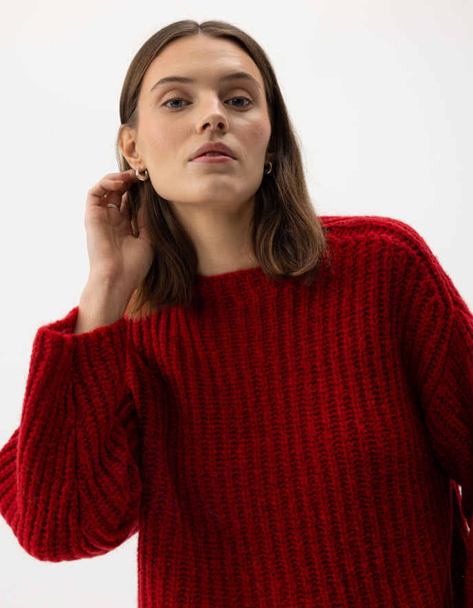 Woman wearing a red sweater against a white background