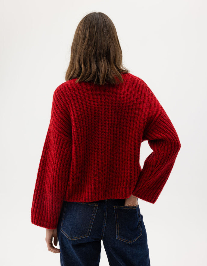 Person wearing a red sweater and blue jeans on a white background