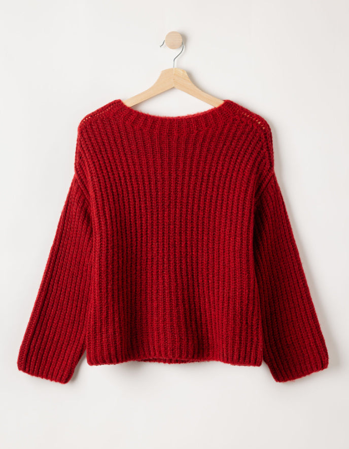 Red ribbed merino sweater on a wooden hanger against a white background