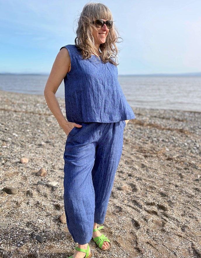 Woman in a blue outfit standing on a beach with ocean in the background