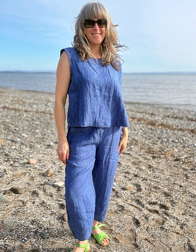 Woman in a blue outfit standing on a beach with ocean in the background