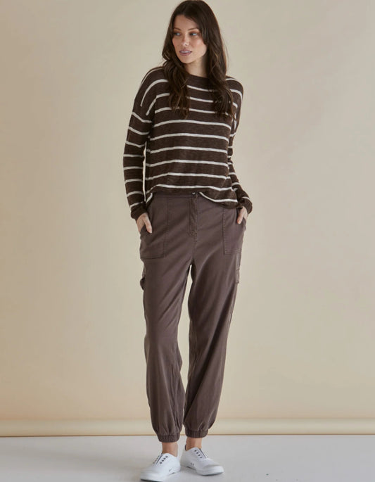 Woman wearing a striped sweater and brown cargo pants against a beige background
