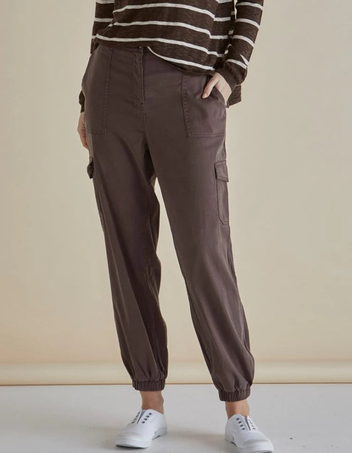 Woman wearing a striped sweater and brown cargo pants against a beige background
