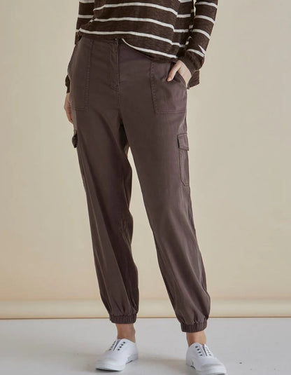 Woman wearing a striped sweater and brown cargo pants against a beige background