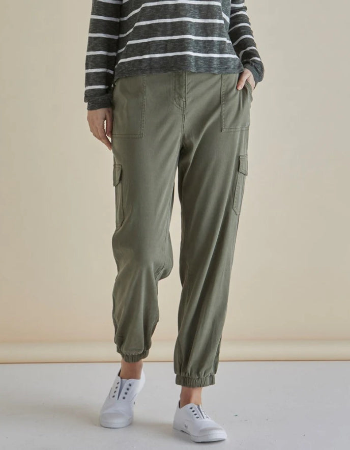 Person wearing green cargo pants and a striped sweater against a beige background