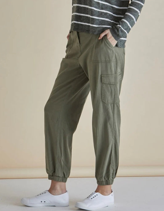Person wearing olive green cargo pants with a striped sweater and white sneakers on a beige background