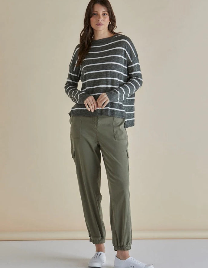 Woman wearing a striped sweater and cargo pants against a plain background