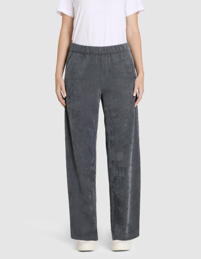 Person wearing grey wide leg corduroy pants on a white background