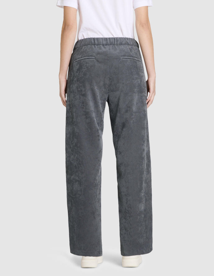 Person wearing grey wide leg corduroy pants on a white background