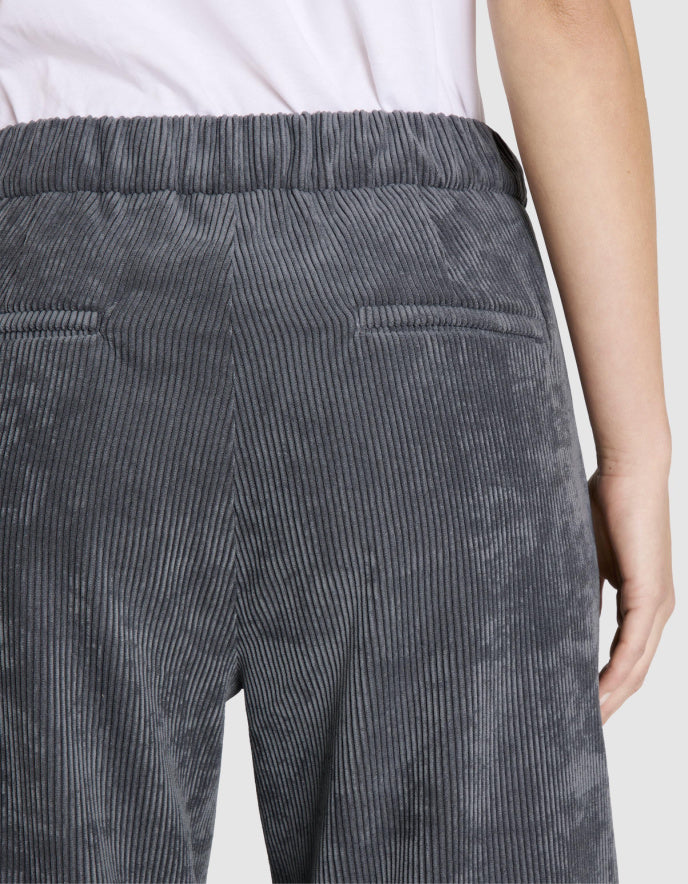 Person wearing grey wide leg corduroy pants on a white background