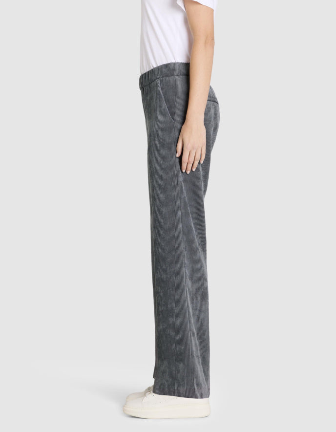 Person wearing grey wide leg corduroy pants on a white background