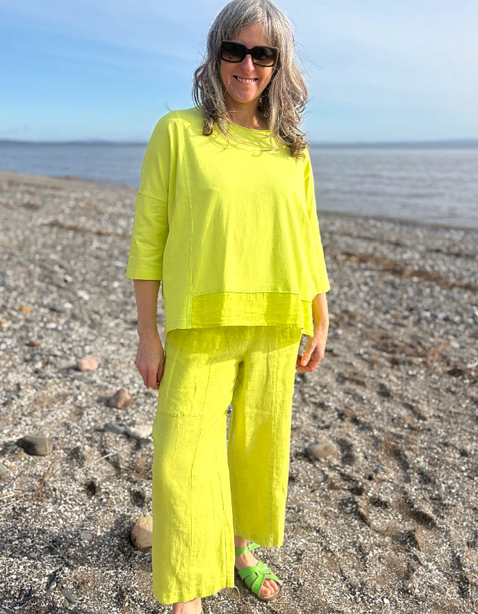 Woman in bright yellow outfit standing on a beach